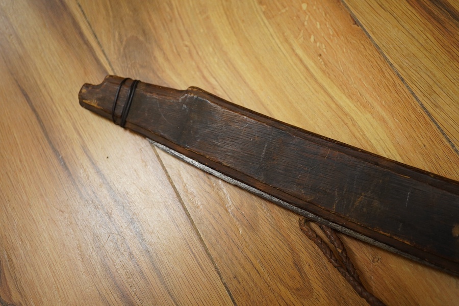 An elaborate Dayak headhunter’s sword Mandau, curved blade with chiselled and engraved back edge, large bone grip carved with protruding teeth, etc. in its wooden scabbard. Condition - good, some age wear.